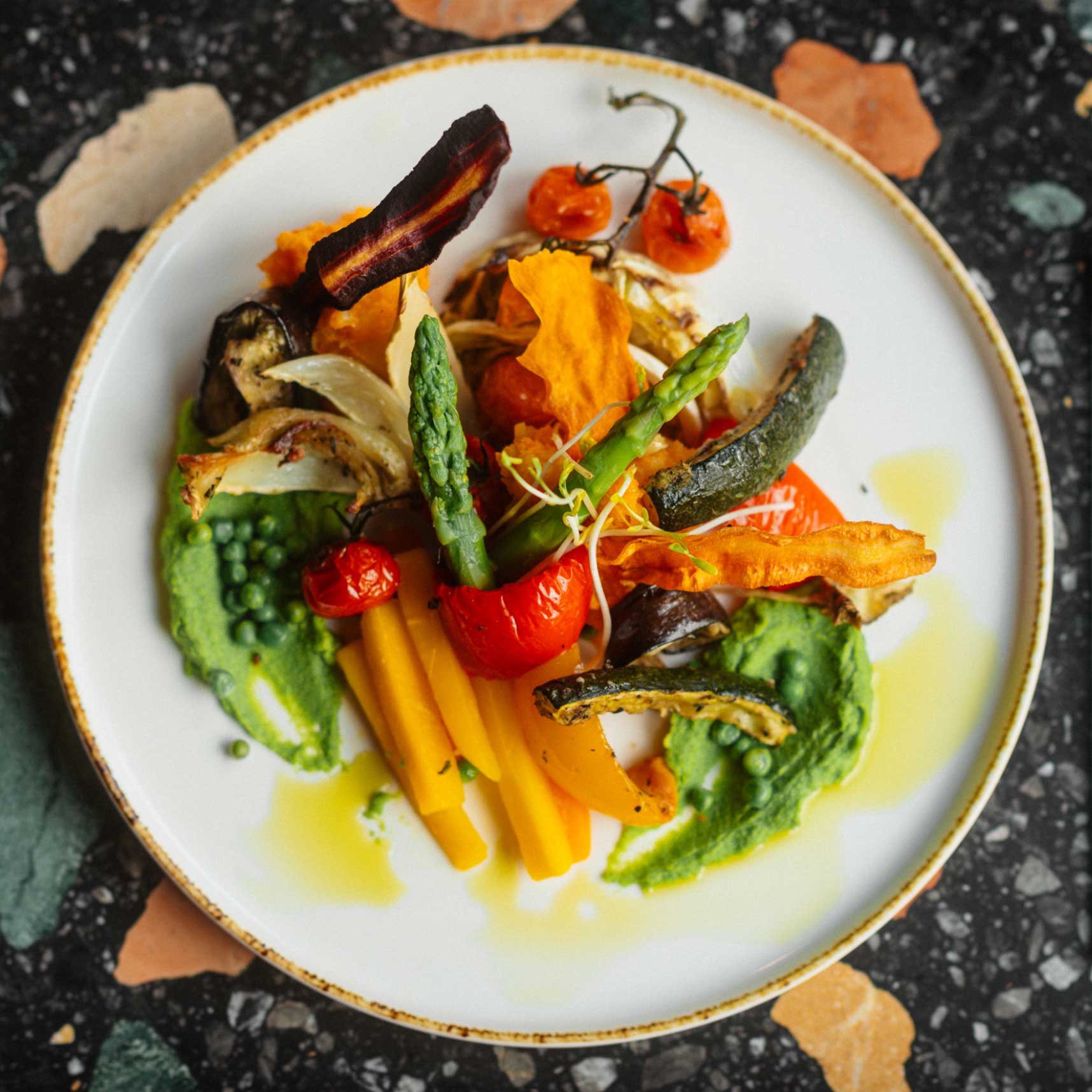 anouki_visual_home4 Anouki Restaurant Düsseldorf, Teller beige, handgetöpfert, Essen, Grillgemüse, Möhren, Karotten, Erbsenmuss, Paprika, grüner Spargel, Pilze, Bacon, Aubergine, Tomaten