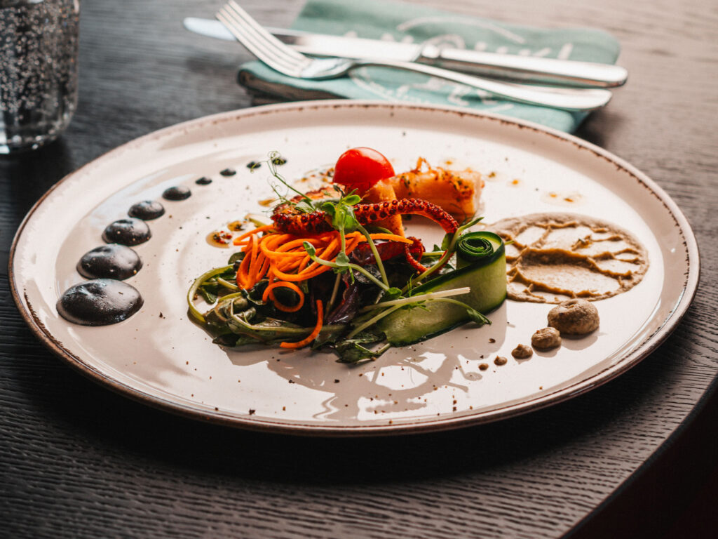Anouki Restaurant Düsseldorf, Teller beige, handgetöpfert, Essen, Möhren, Zucchini Rollen, gegrillter Tintenfisch